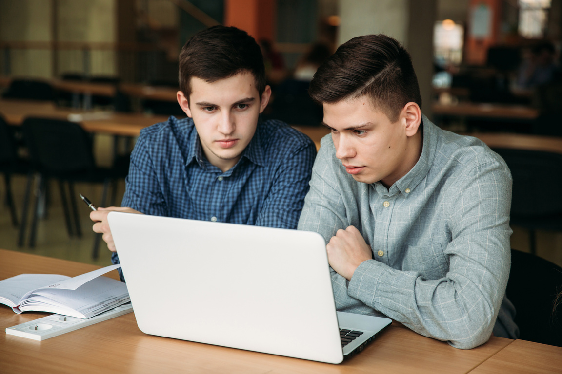 Male Students Use Laptop in Library